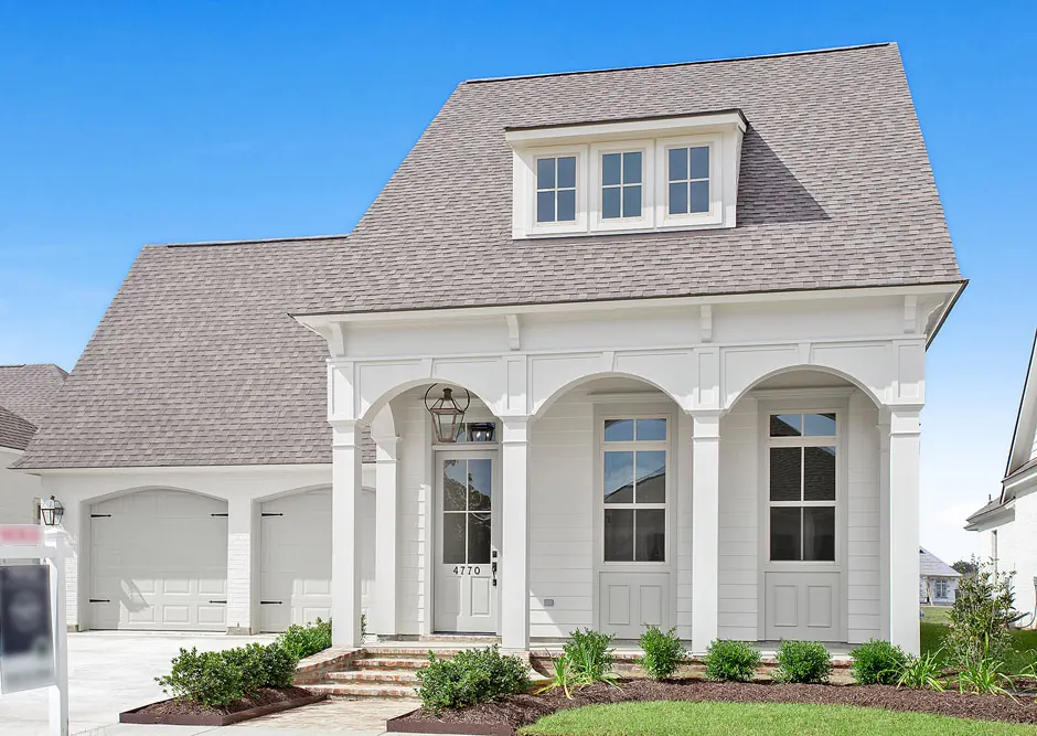 White custom home with a triple-arched front porch, dormer and brick steps in The Village at Conway