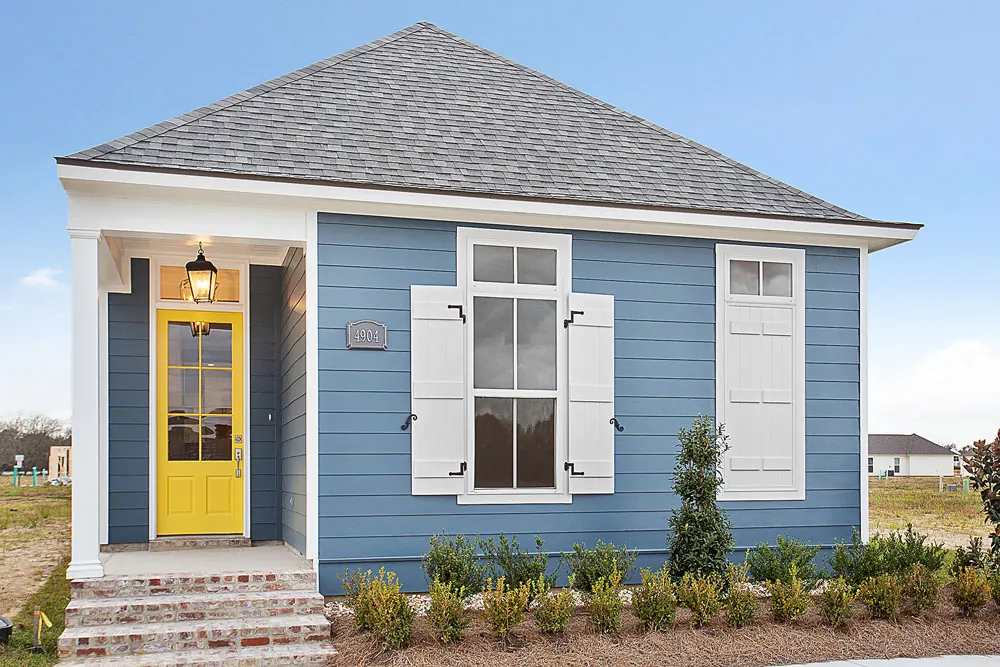 Blue cottage with a yellow front door, white shutters and a gas lantern in Conway