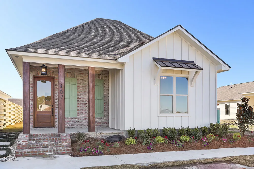 Board-and-batten cottage with a brick and cedar front porch and green shutters in Conway