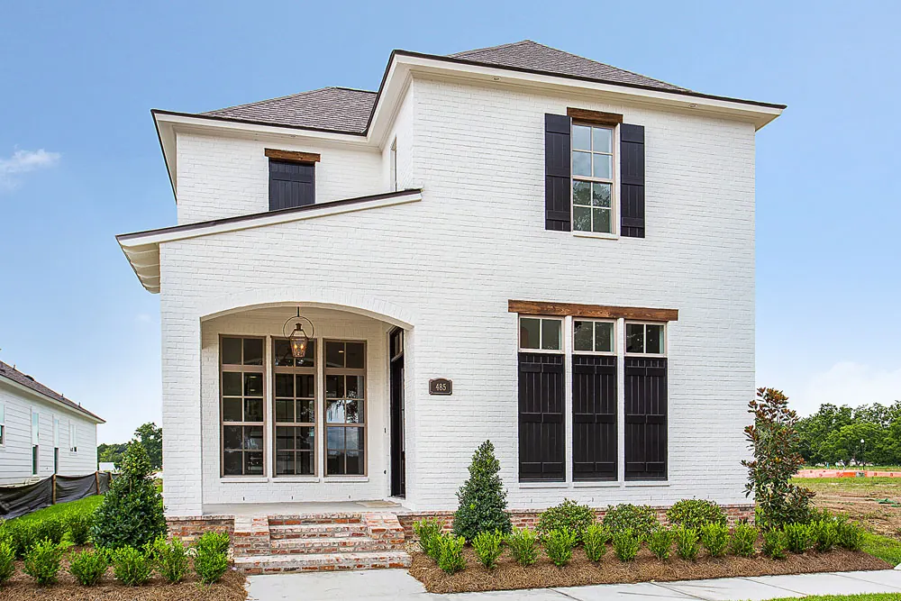Two-story white painted brick home with black shutters and an arched entry in Conway