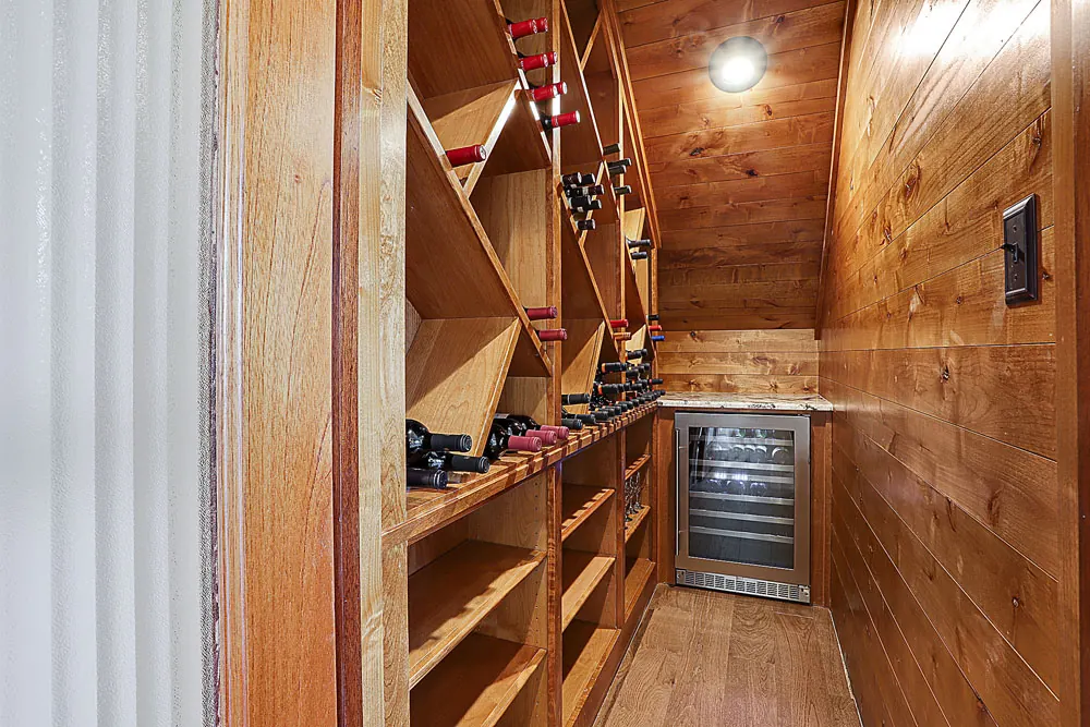 Wood-lined wine room with diagonal bottle racks and a wine fridge