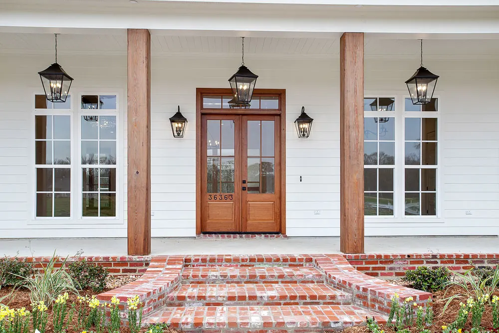 Front porch with cedar columns, copper lanterns, mahogany double doors and wide brick steps