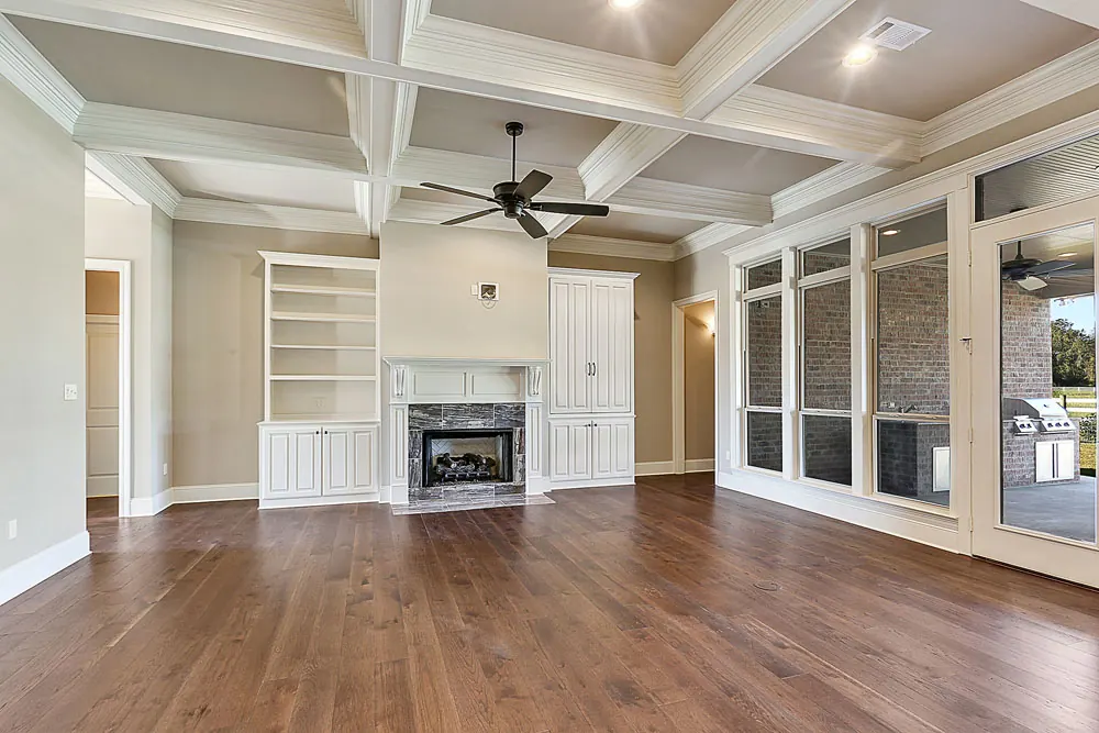 Great room with a coffered ceiling, built-in shelves, a fireplace and a wall of windows